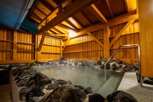 a room with a hot tub in a wooden building at KAMENOI HOTEL Kusatsu Yubatake in Kusatsu