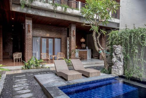 a patio with two chairs and a swimming pool at The Ganesha Homestay in Canggu