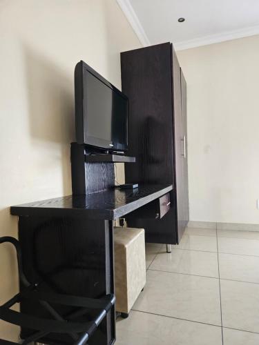 a desk with a television on top of it at Booth Suite Hotel Mafikeng in Mahikeng