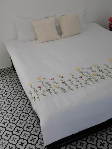 ein Bett mit weißer Bettwäsche und Blumen darauf in der Unterkunft Gạo Homestay in Mui Ne