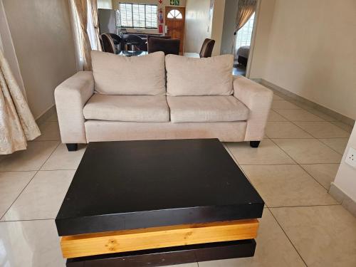 a living room with a couch and a coffee table at Booth Suite Hotel Mafikeng in Mahikeng