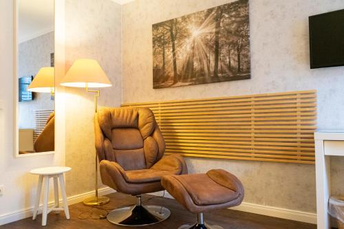 Rein Klassik Hotel في باد بيرمونت: غرفة معيشة فيها كرسي وتلفزيون