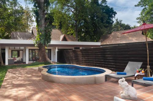 una piscina en un patio con una casa en The Legend Chiang Rai Boutique River Resort & Spa, en Chiang Rai