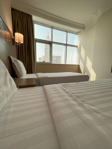 a hotel room with two beds and a window at Nawazi Towers Hotel in Makkah