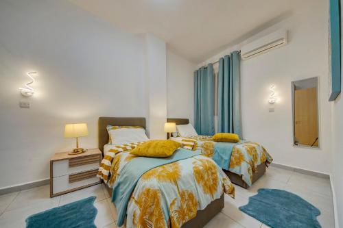 two beds in a bedroom with two blue rugs at St Julians apartment 1 in St Julian's