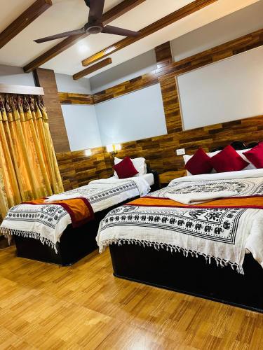 two beds in a room with wooden walls at Hotel Riverside with Swimming pool in Sauraha