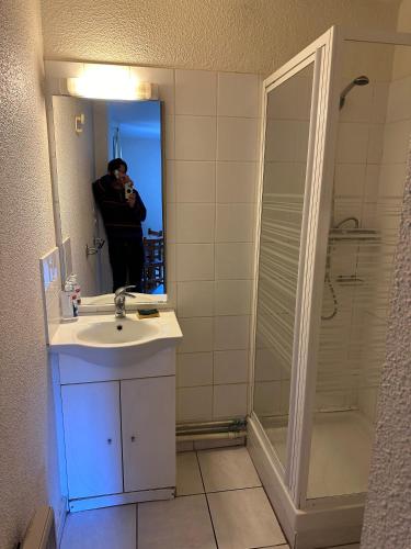 un homme prenant une photo d'une salle de bains avec lavabo et douche dans l'établissement Studios Corenc, à Corenc