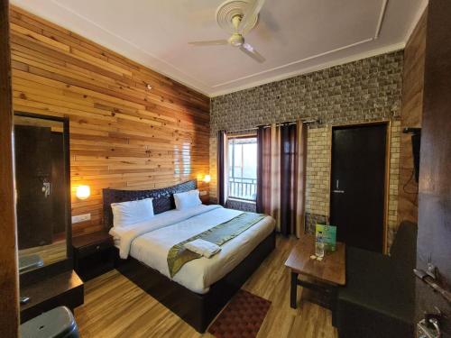 1 dormitorio con 1 cama y pared de madera en SH SUNSET RESORT en Nainital