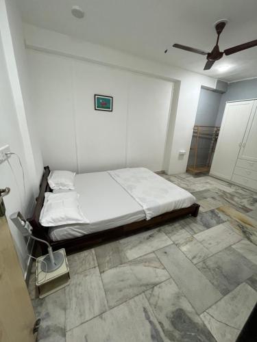 ein weißes Schlafzimmer mit einem Bett und einem Deckenventilator in der Unterkunft 3BHK Duplex Service Apartment near Riverfront in Ahmedabad