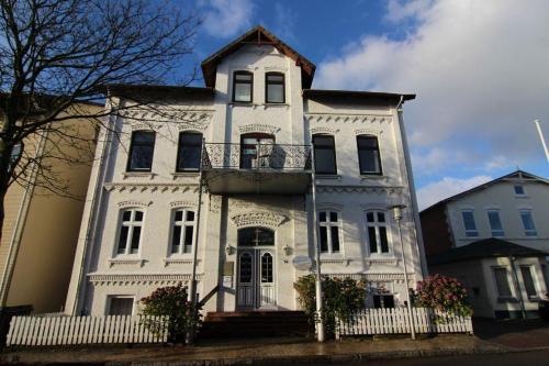 uma grande casa branca com uma cerca branca em Kapitaenshaus-Lassen-Zimmer-Sindbad em Westerland