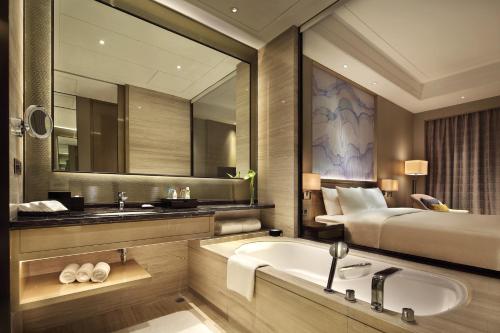 a bathroom with a bed and a sink and a tub at Wanda Realm Huangshi in Huangshi