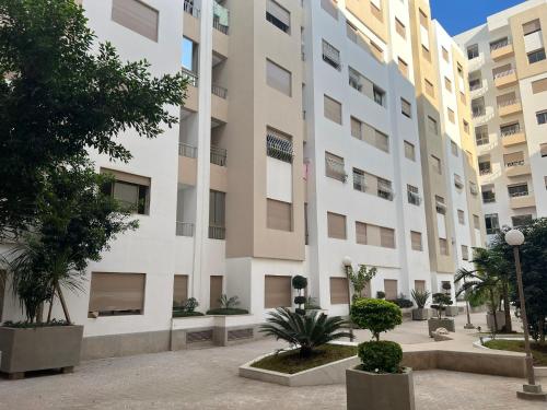 un grand bâtiment blanc avec des arbres devant lui dans l'établissement Appartement Jardins de Tanger , 2 chambres, à Tanger
