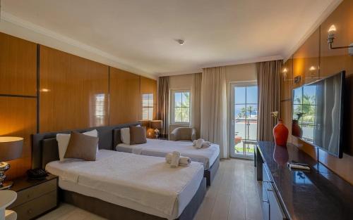 une chambre d'hôtel avec deux lits et une télévision dans l'établissement Golden Beach Resort & Spa, à Bodrum City