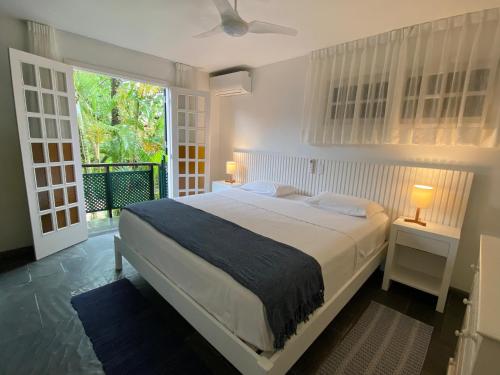 a bedroom with a bed and a large window at Juquehy - Condomínio de Frente para o Mar - Piscina Aquecida - Quadra de Tenis in Juquei