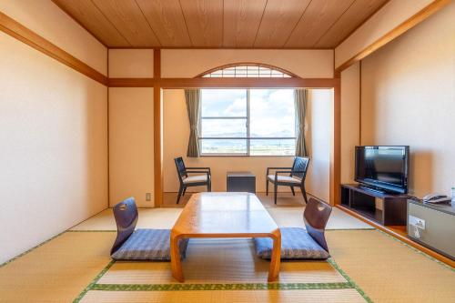 sala de estar con mesa, sillas y TV en Ooedo Onsen Monogatari Aizu, en Aizuwakamatsu