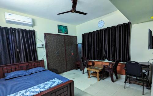 a bedroom with a bed and a desk and chairs at GKV Service Apartment Saligramam in Chennai