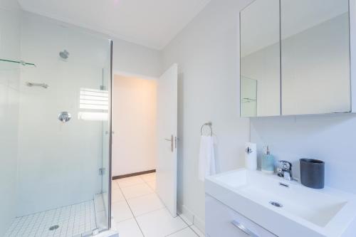 a white bathroom with a sink and a shower at Luxury Home with an Office & Backup Power in Sandton