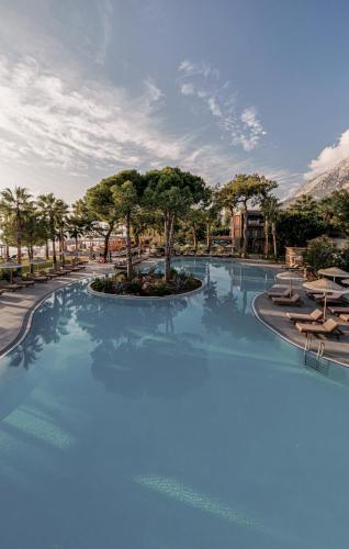 a large swimming pool with chairs and trees at Balmy Beach Resort Kemer in Kemer