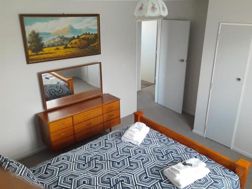 Dormitorio con cama con espejo y tocador en Anchors Away (the boaties paradise) en Whanganui