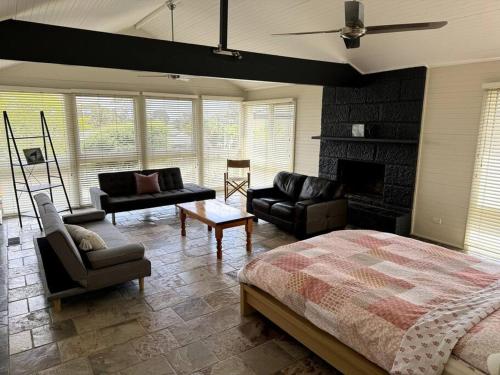 1 dormitorio con cama, sofás y chimenea en Relax, Resort Style, en Rosebud