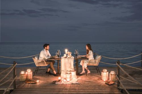 a man and woman sitting at a table on the beach at Balmy Beach Resort Kemer in Kemer