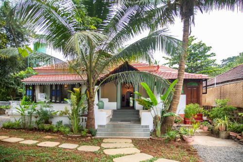 Lamrin Ucassaim Goa A 18th Century Portuguese Villa في Moira: منزل أمامه أشجار نخيل