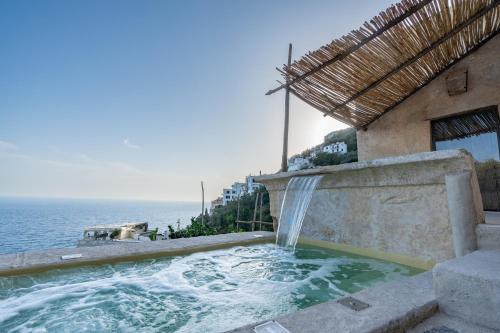 a water fountain outside of a building next to the ocean at Aurora apartment in Alma Domus in Amalfi