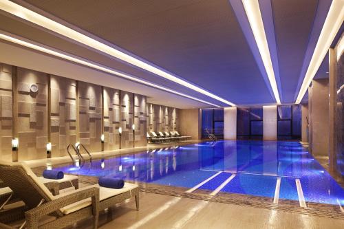 a large swimming pool in a hotel with blue lighting at Wanda Realm Huangshi in Huangshi