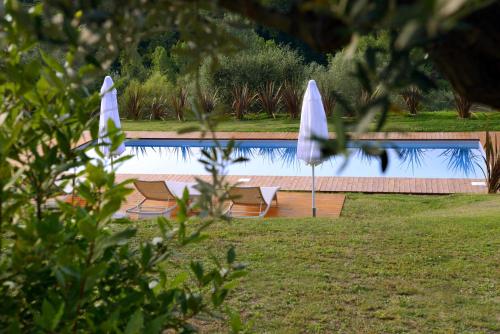a swimming pool with two umbrellas and two chairs at Country House I Lauri in Montefiore dellʼAso