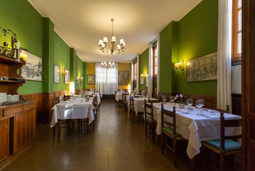 ein Esszimmer mit Tischen und grünen Wänden in der Unterkunft Antica Trattoria dell'Uva in Monza