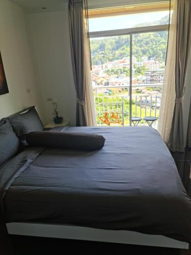 a bedroom with a bed with a large window at Art Patong Residence in Patong Beach