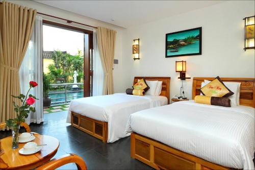 2 camas en una habitación de hotel con balcón en villa Trúc Huy, en Tân Thành (1)