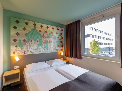 B&B Hotel Neuss في نويس: غرفة نوم بسرير ونافذة كبيرة