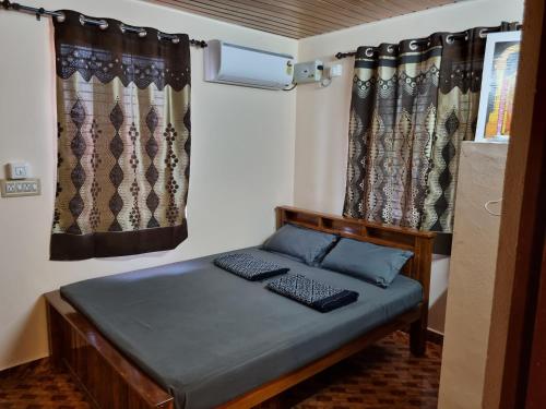 Cama en habitación pequeña con cortinas en Maison Parnakuti Adigas Homestay Dharmasthala Guest House Hotel Room, en Dharmastala