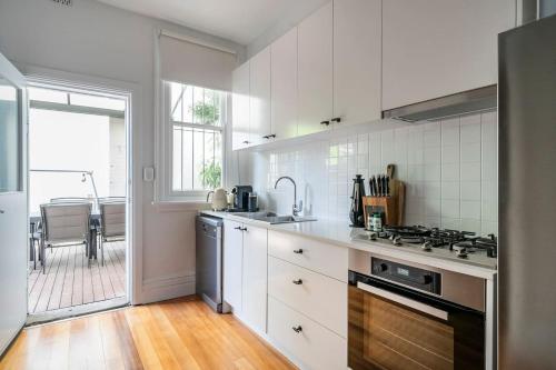 a kitchen with white cabinets and a stove top oven at Newtown Nest - Chic Terrace Living off King Street in Sydney