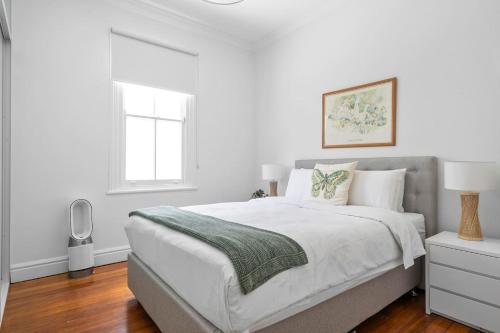 a white bedroom with a bed and a window at Newtown Nest - Chic Terrace Living off King Street in Sydney