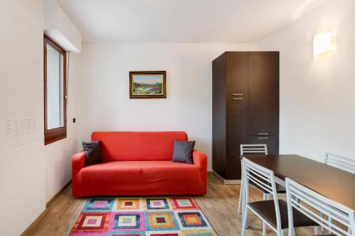 a living room with a red couch and a table at Le Sorgenti - Piano terra in Valdisotto
