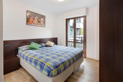 a bedroom with a bed with a plaid blanket at Le Sorgenti - Piano terra in Valdisotto