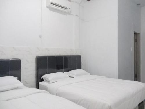 Dos camas en una habitación con sábanas blancas. en Hotel 889 Syariah Redpartner Banda Aceh, en Banda Aceh