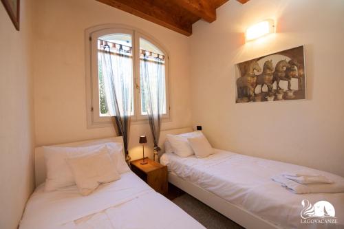 2 aparte bedden in een kamer met een raam bij Borgo del Torchio - App. 5H in Manerba del Garda