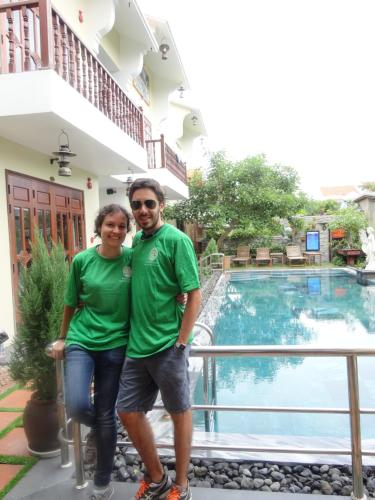 a man and a woman standing next to a swimming pool at villa Trúc Huy in Tân Thành (1)