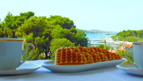 a plate of waffles on a table next to two cups at Boutique Apartments Refresh in Vodice