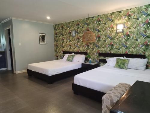 2 camas en una habitación de hotel con papel pintado en RedDoorz @ Padi Beach Resort Oton Iloilo en Oton