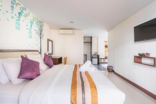 a bedroom with a large white bed with purple pillows at Manee Cool Mueang in Chiang Mai