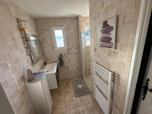 a bathroom with a shower and a sink and towels at LES CLÉMATITES in Donzère