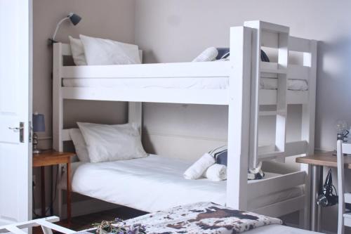 a bedroom with two bunk beds with white furniture at De Akker Guest House Oudtshoorn in Oudtshoorn