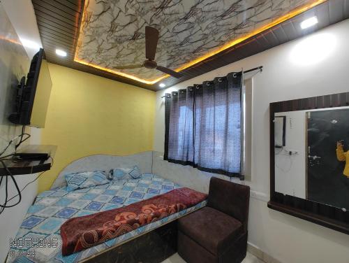 a bedroom with a bed and a chair in it at Hotel Unnat Shree. in Pachmarhī