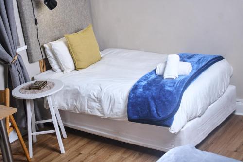 a small bed with a blue blanket on it at De Akker Guest House Oudtshoorn in Oudtshoorn