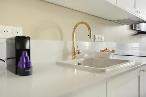 - un comptoir de cuisine blanc avec un évier et un robinet dans l'établissement Apartment Opéra by Studio prestige, à Paris