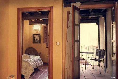 1 dormitorio con 1 cama y balcón con mesa en APARTAMENTOS RURAL LA JACOBA, en Cabezuela del Valle
